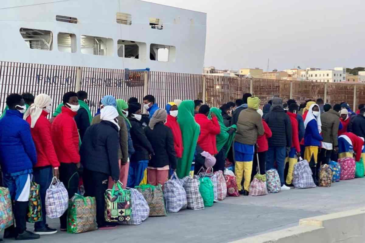 migranti in fila in un centro di accoglienza