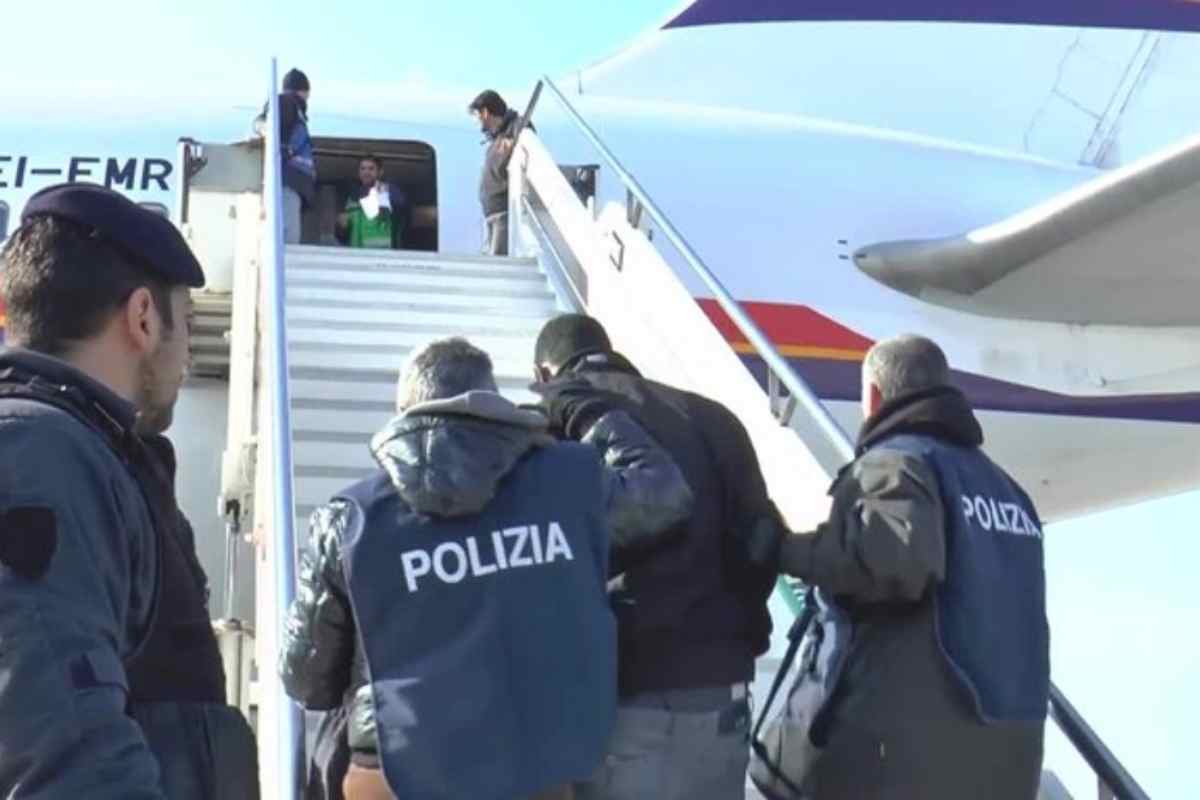 Alcuni poliziotti portano a bordo di un aereo un migrante da rimpatriare