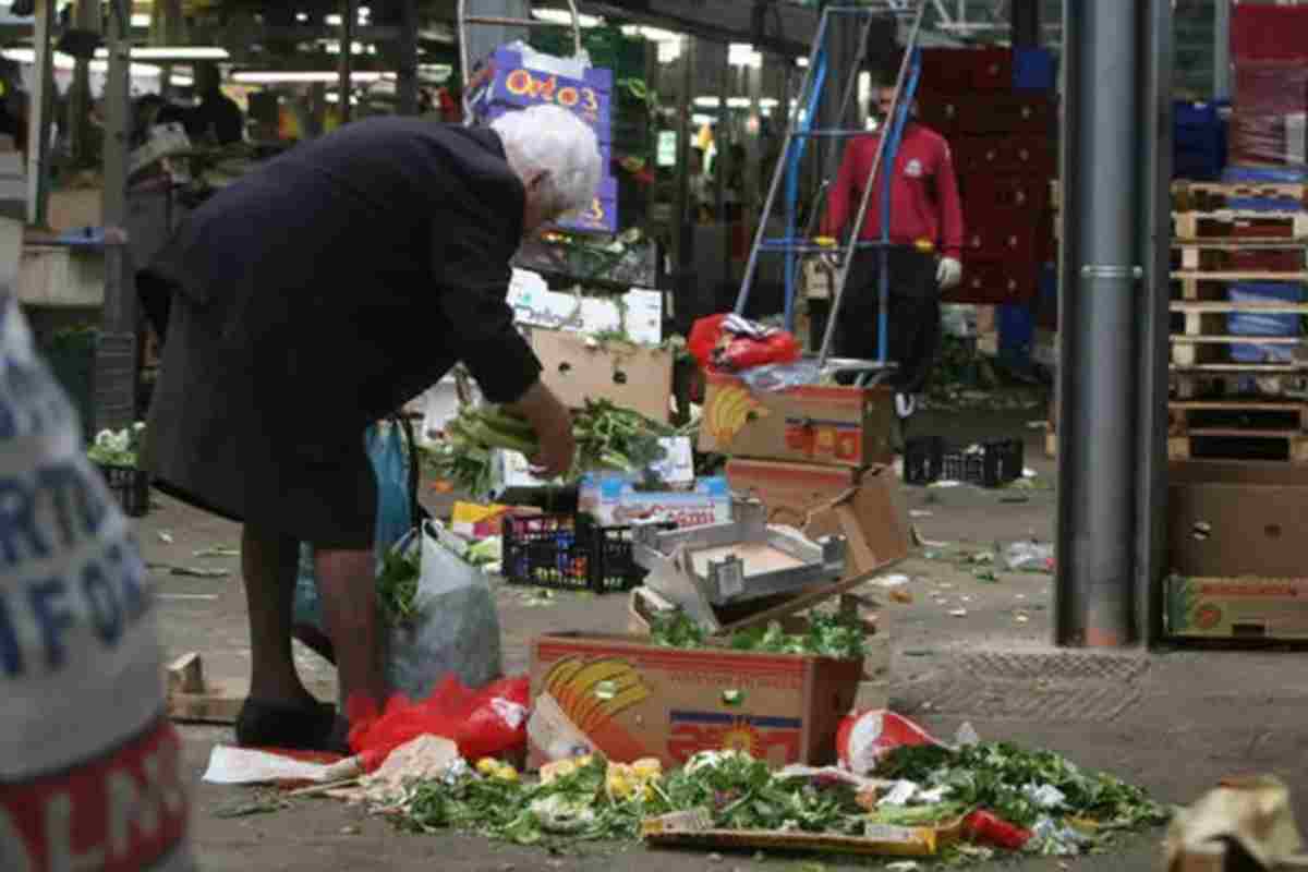 Una signora cerca del cibo nella spazzatura