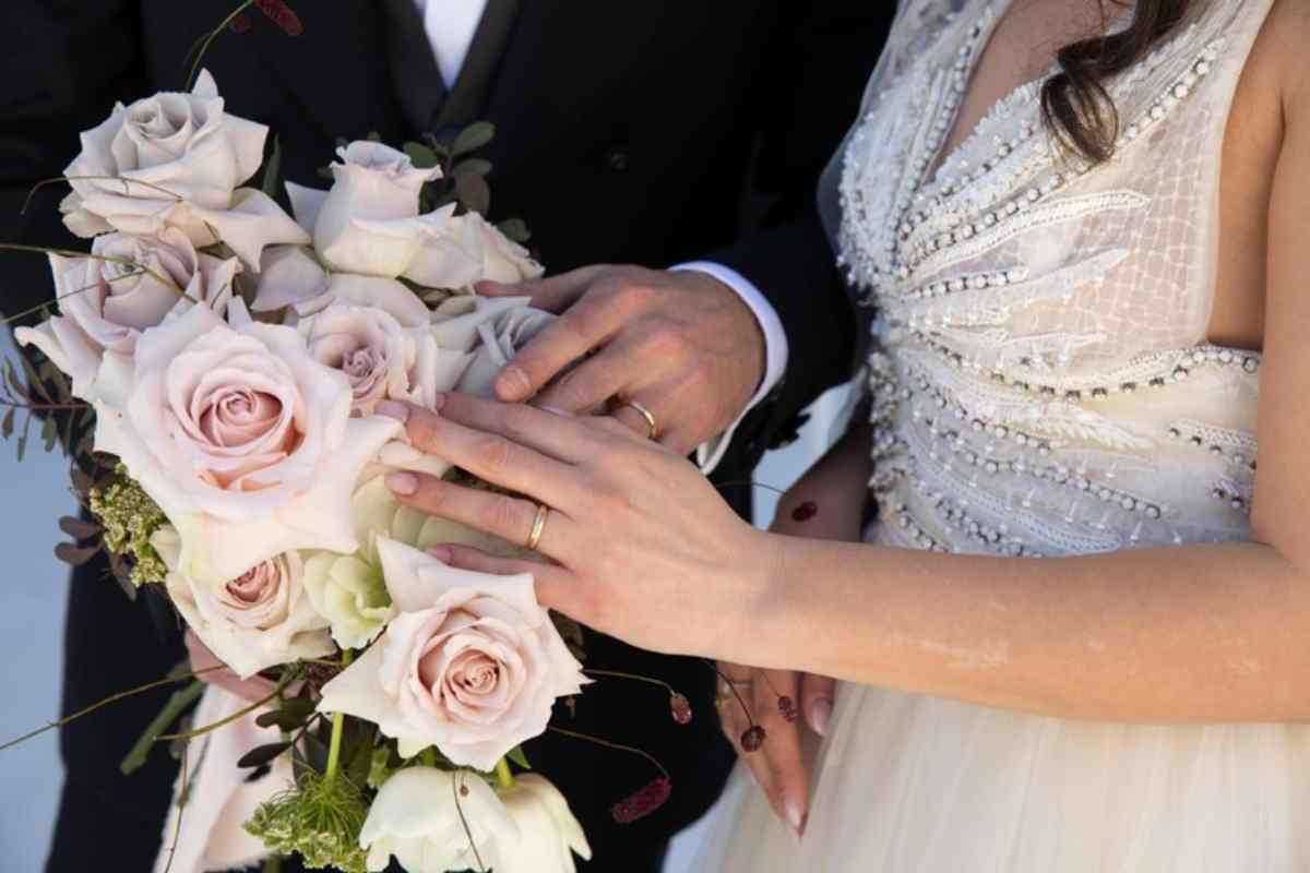 Dettaglio delle mani di un marito e la moglie, con un bouquet di fiori