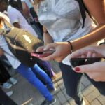 Studenti usano il cellulare fuori scuola