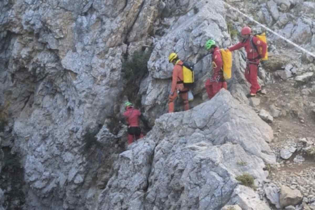 Un gruppo di soccorritori speleologi che camminano in fila indiana tra le rocce