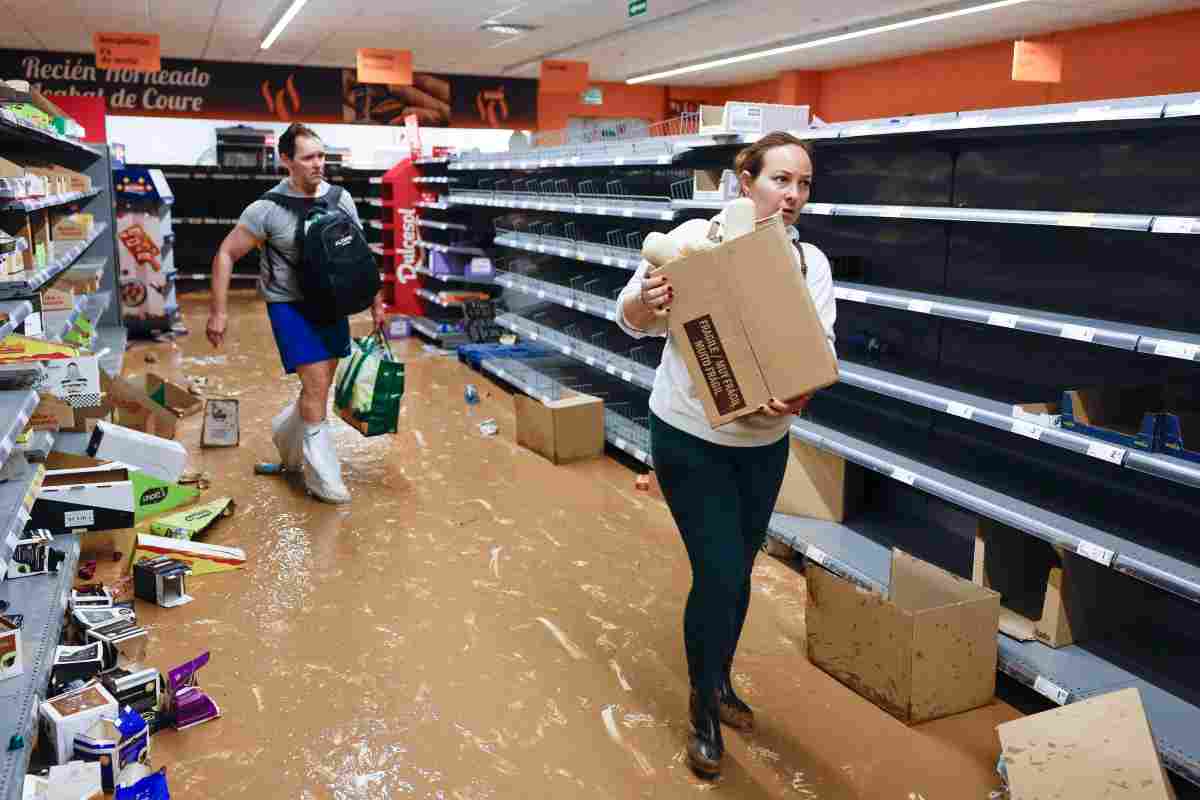 Gente porta via i prodotti ancora disponibili all'interno di un supermercato allagato della provincia di Valencia in Spagna 