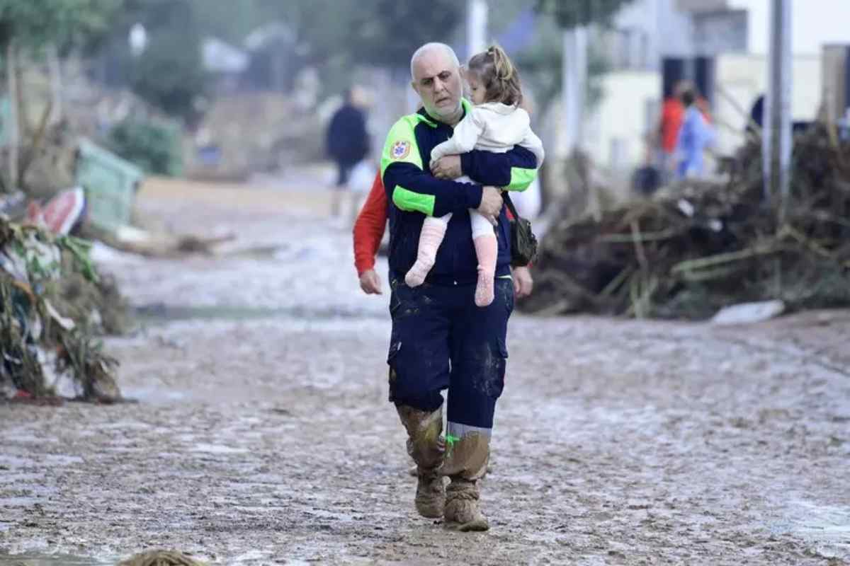 soccorritore con in braccio una bimba nell'alluvione a valencia