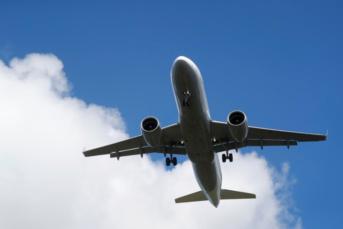 Un aereo di linea in volo fotografato dal basso, con un cielo sereno sullo sfondo