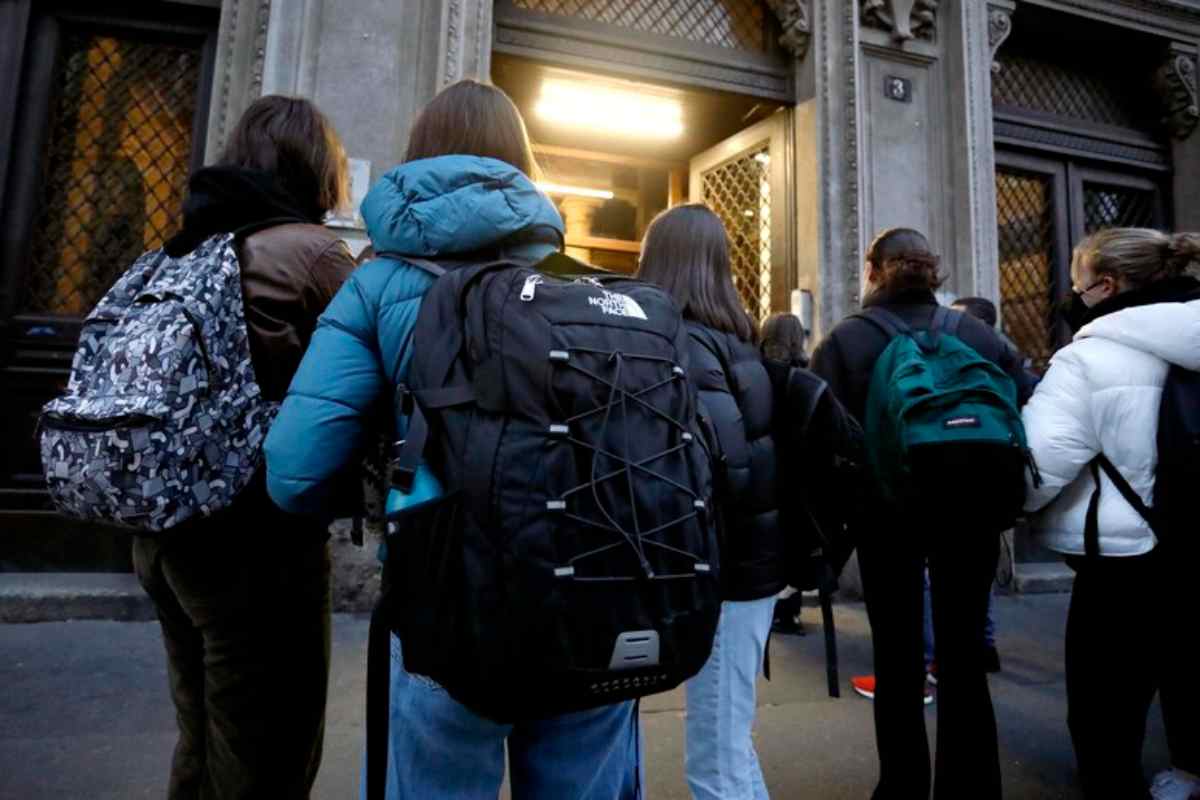 Alcuni studenti con lo zaino in spalla all'entrata di una scuola