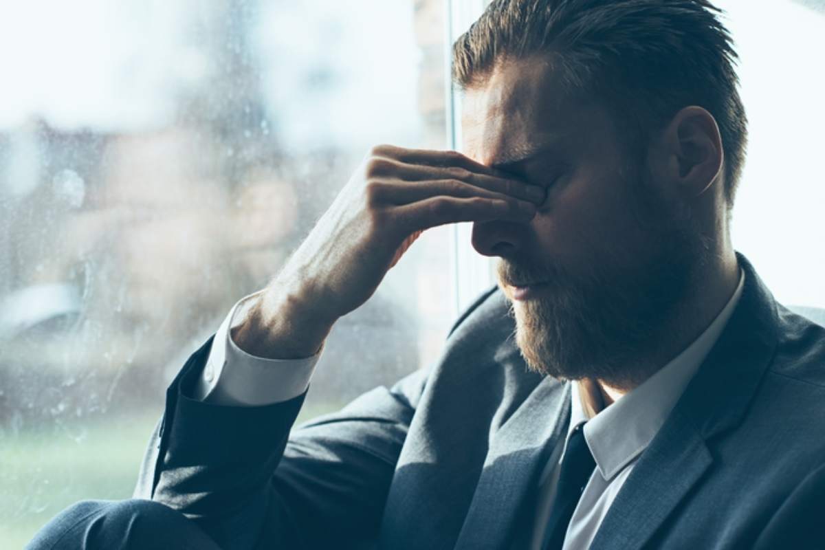 Un uomo disperato con la mano sugli occhi