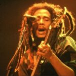 Bob Marley mentre suona la chitarra e canta durante un concerto