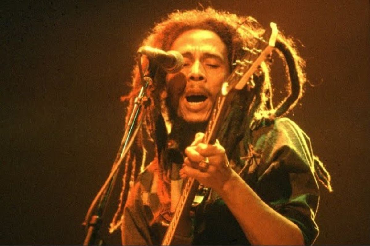 Bob Marley mentre suona la chitarra e canta durante un concerto