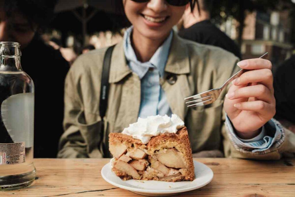 una ragazza mangia una fetta di torta alle mele