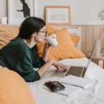 Ragazza che lavora al computer sul letto