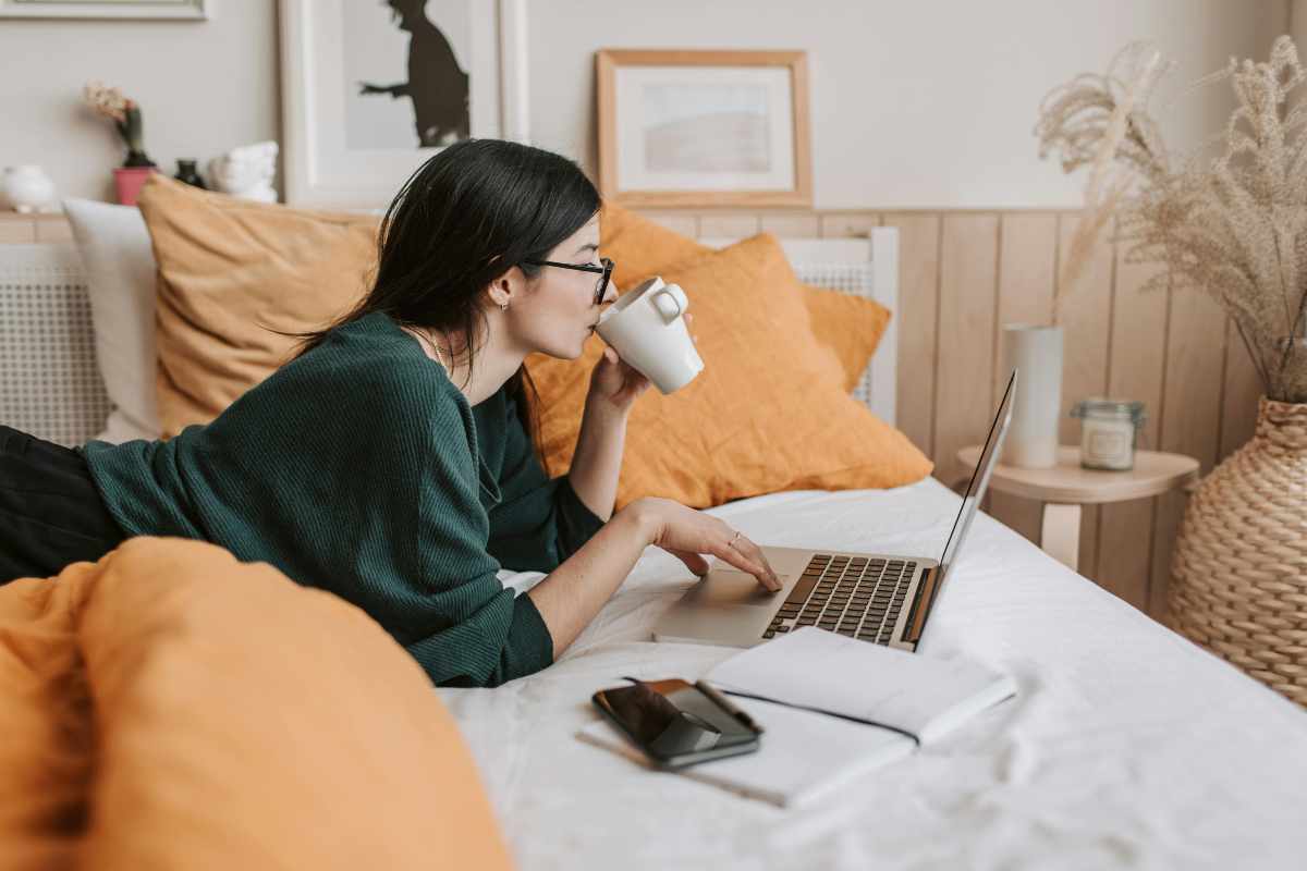 Ragazza che lavora al computer sul letto