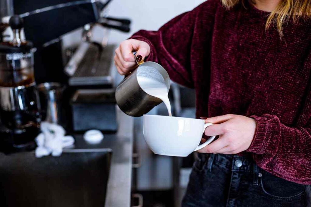 una ragazza prepara un cappuccino al bar