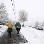 Due persone camminano sulla neve in un paese di montagna