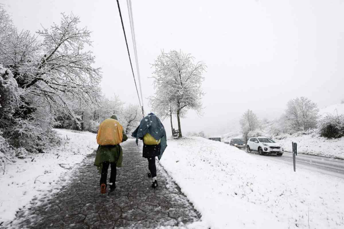 Due persone camminano sulla neve in un paese di montagna