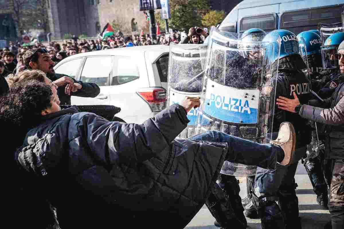 Un manifestante prova a dare un calcio ad un poliziotto