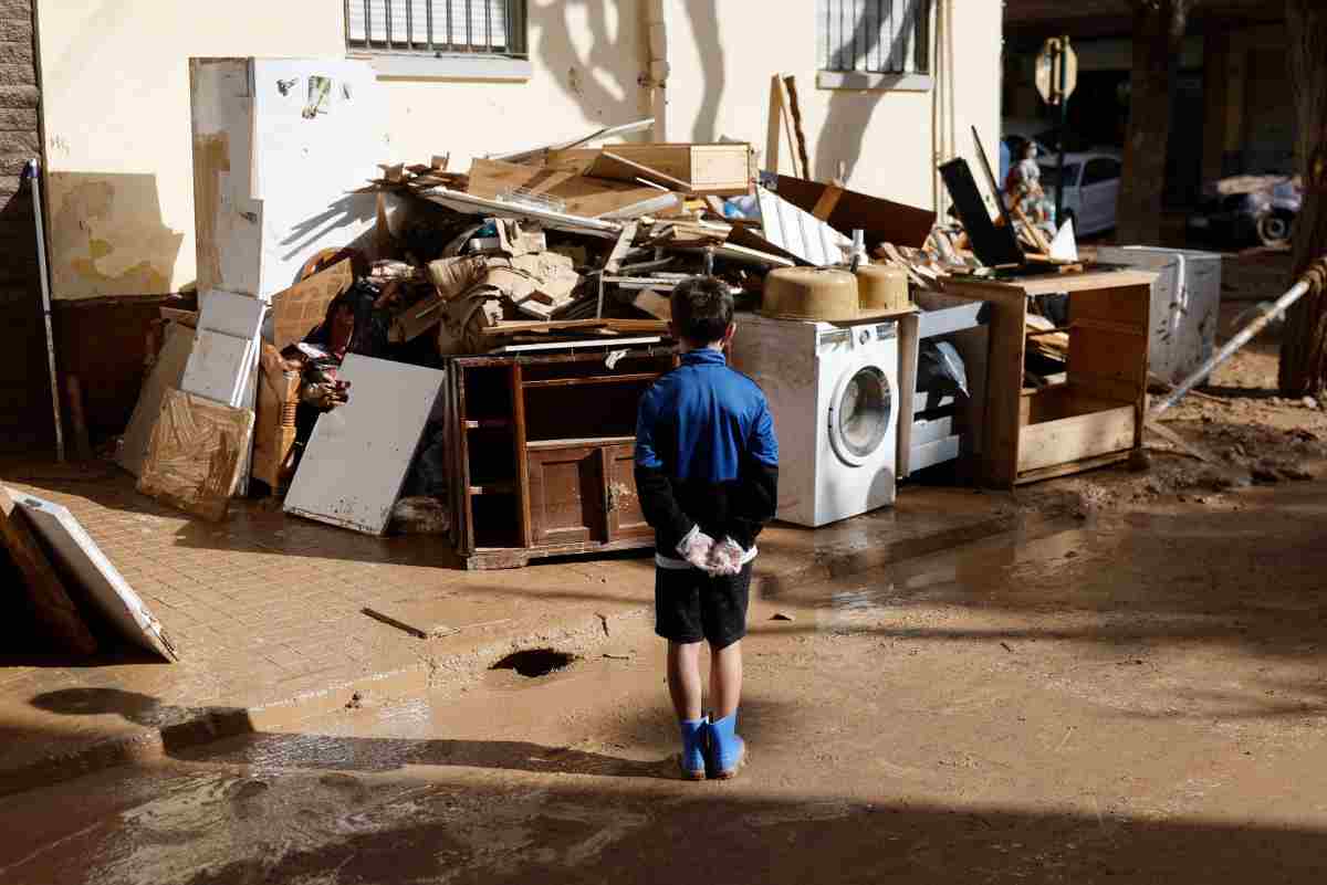 Bamvbino guarda oggetti accatastati a Valencia dopo alluvione