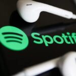 Il logo di Spotify su un cellulare e un paio di cuffie