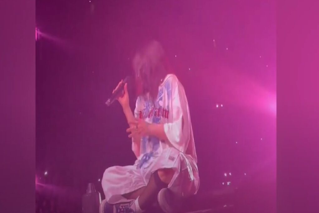 La cantante Billie Eilish seduta sul palco durante un concerto