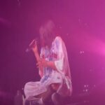 La cantante Billie Eilish seduta sul palco durante un concerto