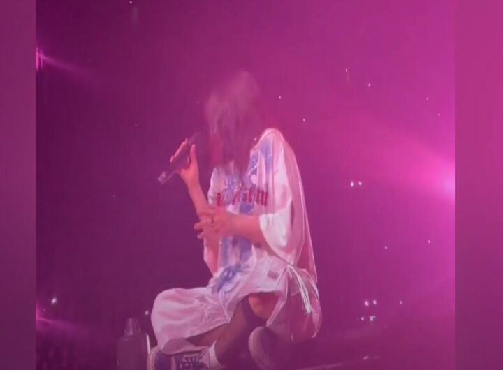 La cantante Billie Eilish seduta sul palco durante un concerto