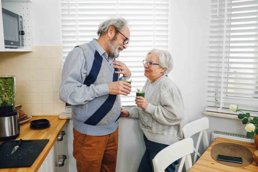 due persone mature in cucina bevono un frullato