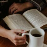 una ragazza beve un caffè mentre legge un libro