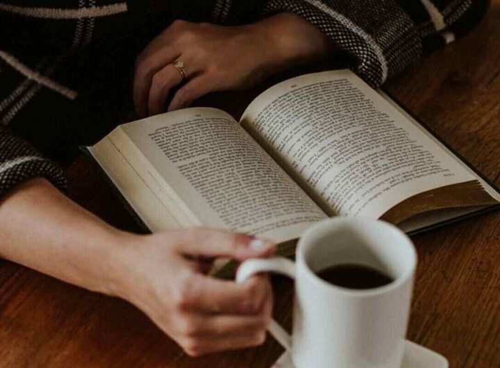 una ragazza beve un caffè mentre legge un libro