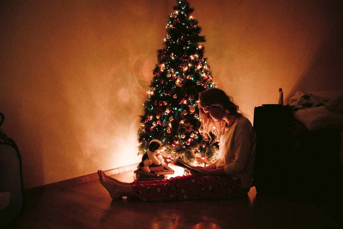 una ragazza seduta vicino ad un albero di Natale