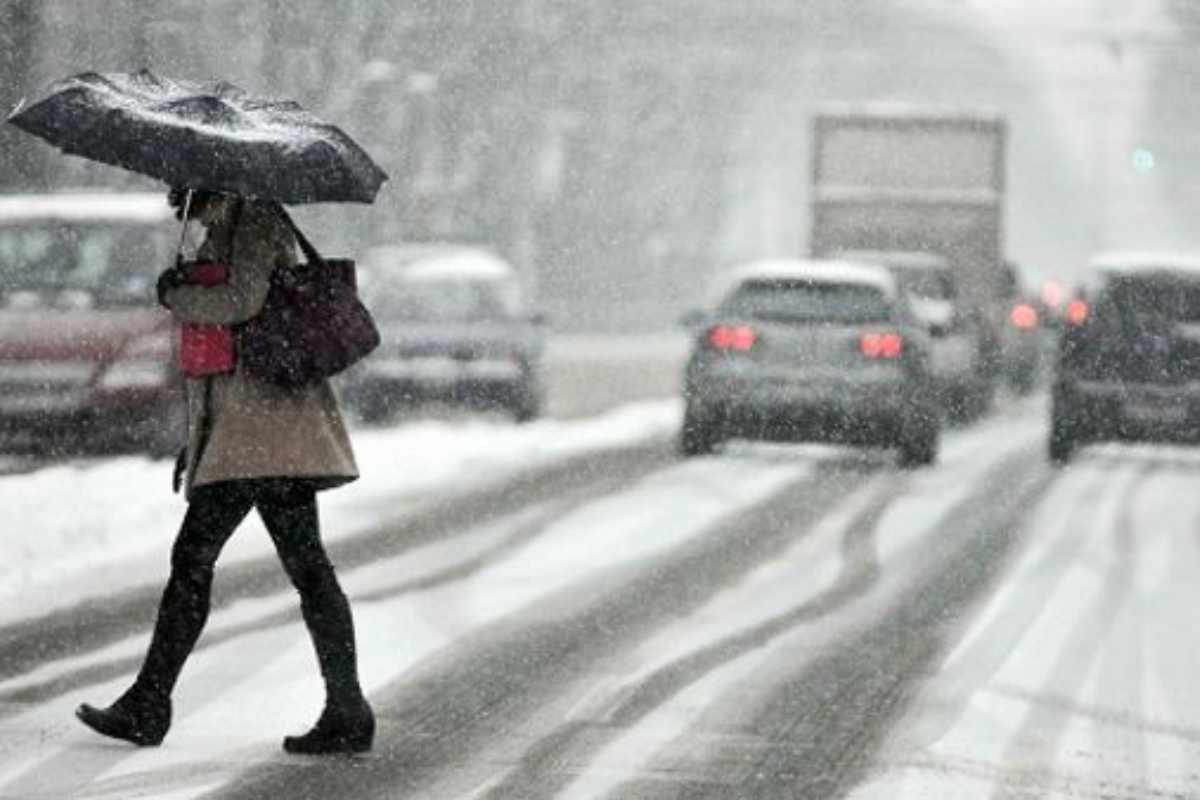 donna attraversa una strada innevata