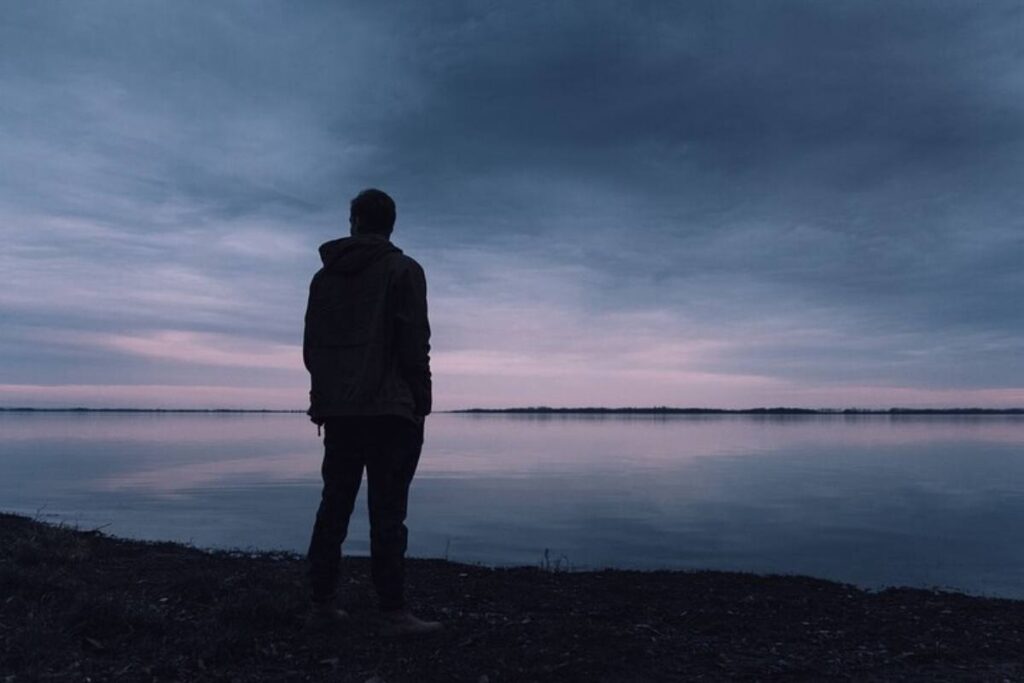 Un uomo al tramonto vicino alla riva