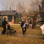 Police officers remove an elderly resident from her home during the Eaton Fire in Altadena