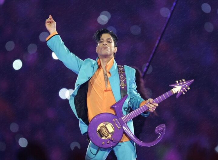 Prince sul palco durante un'esibizione, con la sua caratteristica chitarra viola