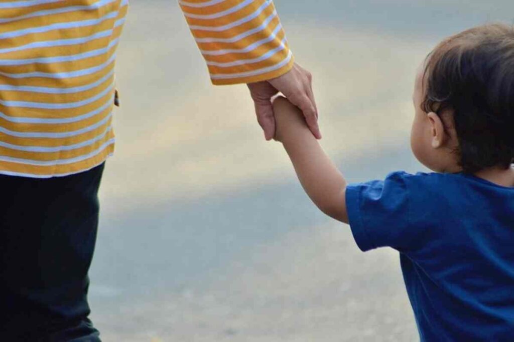 Un bambino tiene la mano ad un adulto